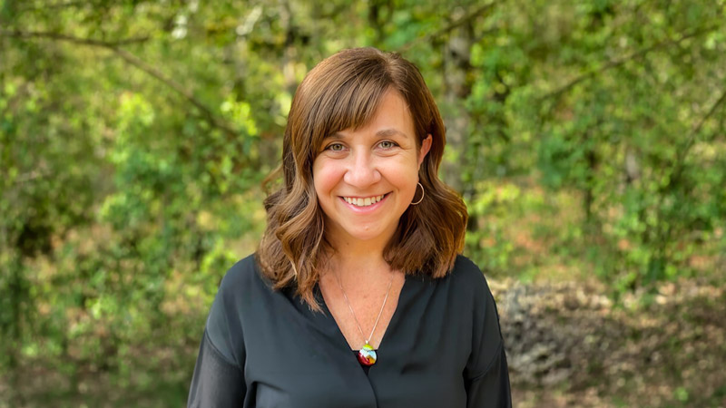 Lisa L. Templeton, Oregon State University's vice provost of educational ventures, smiles while standing in a forested area.