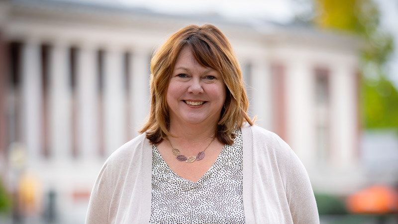 Shannon Riggs of Oregon State University stands smiling outdoors in front of OSU's Memorial Union, with the building's columns blurred in the background.