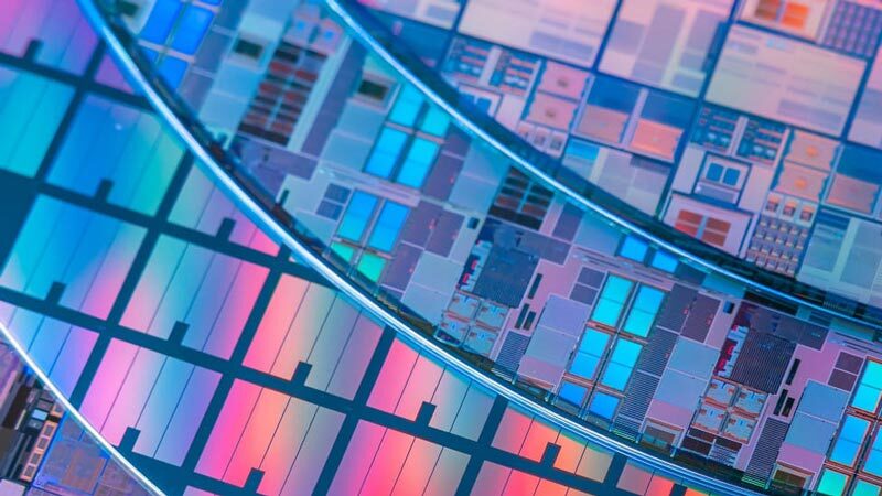 A close-up of colorful semiconductor wafers with intricate circuit patterns used in microchip manufacturing.